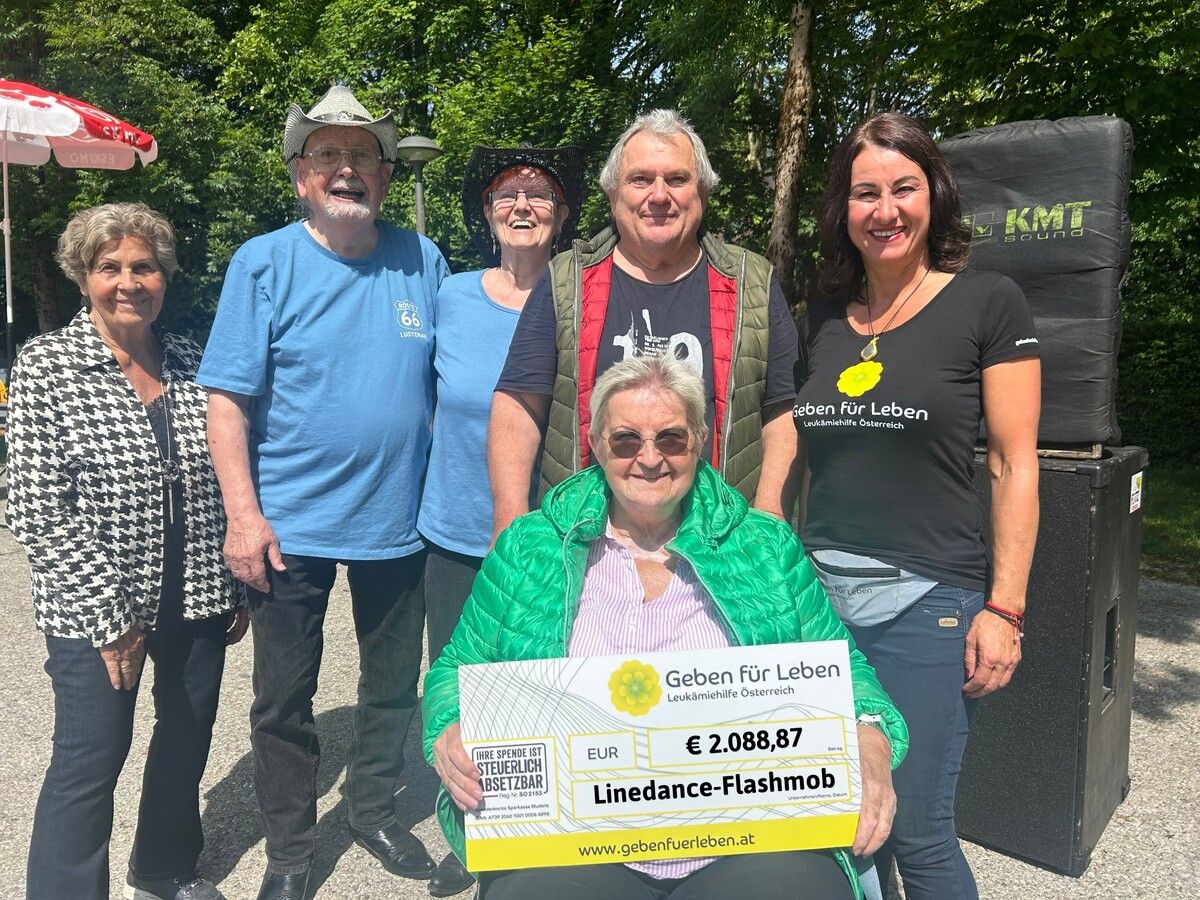 Spende für „Geben für Leben“: Susanne Marosch (r.) und Mitarbeitende freuen sich über den Erlös von Barbara Bayers (v.) Flashmob.