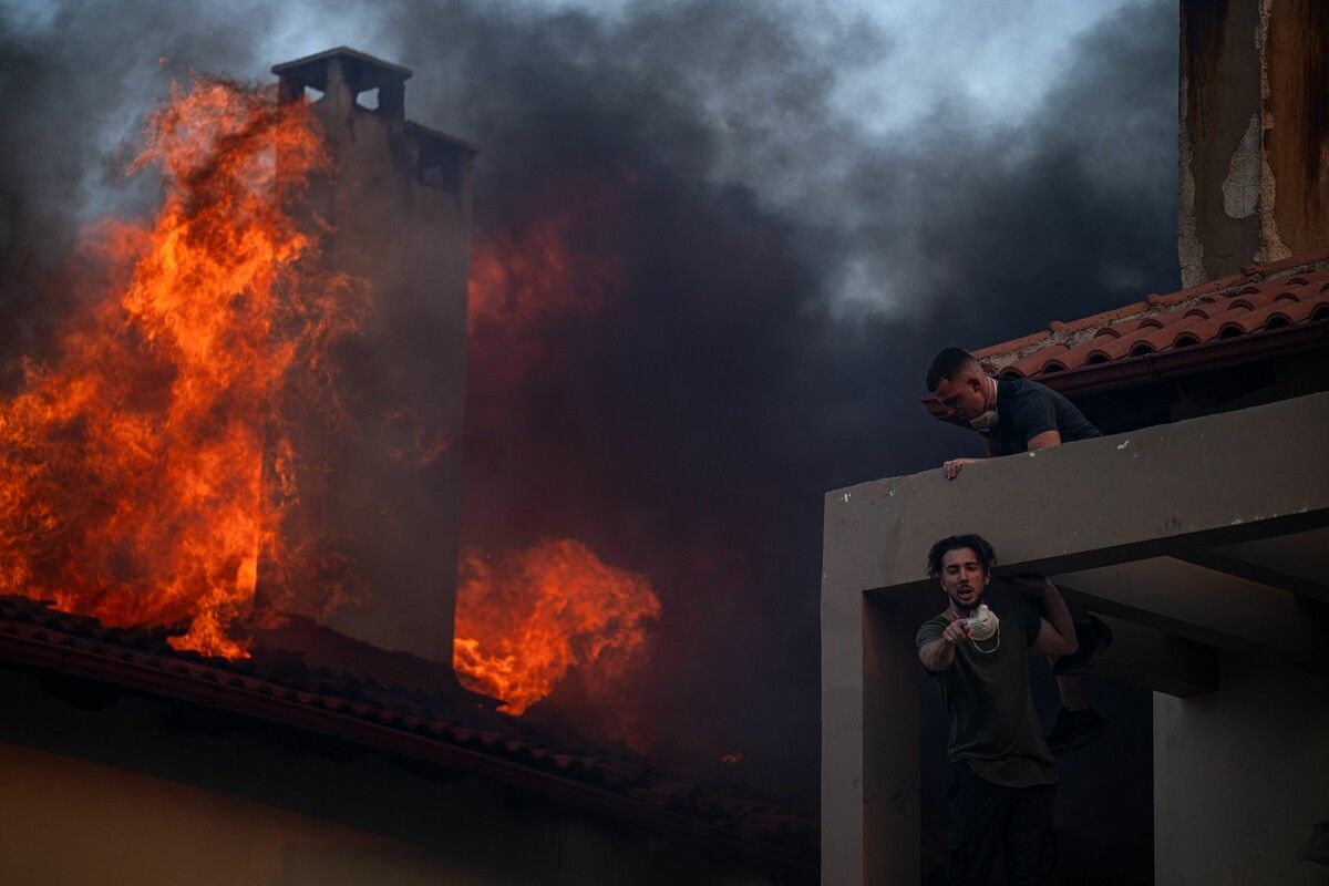Bewohner versuchen, ihre Häuser nahe Athen vor den Flammen zu retten. ⇒AFP