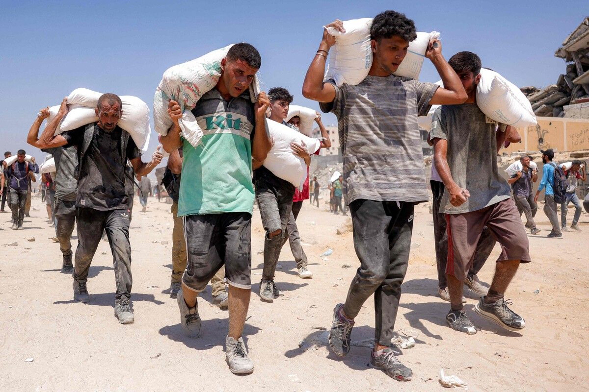 Menschen im Gazastreifen tragen Säcke mit Mehl und Reis zu ihrer Unterkunft.⇒AFP