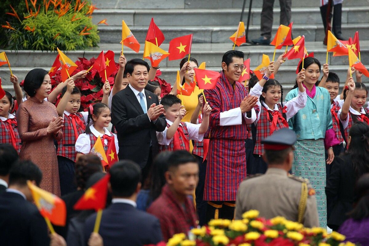 Bhutans König Jigme Khesar, Königin Jetsun Pema, Vietnams Präsident Luong Cuong und seine Frau werden in Hanoi von Kindern mit Flaggen begrüßt. AFP (5)
