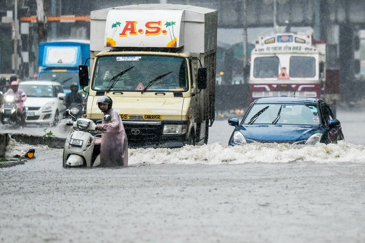 Fahrzeuge kämpfen sich nach starken Regenfällen durch eine überflutete Straße in Mumbai.