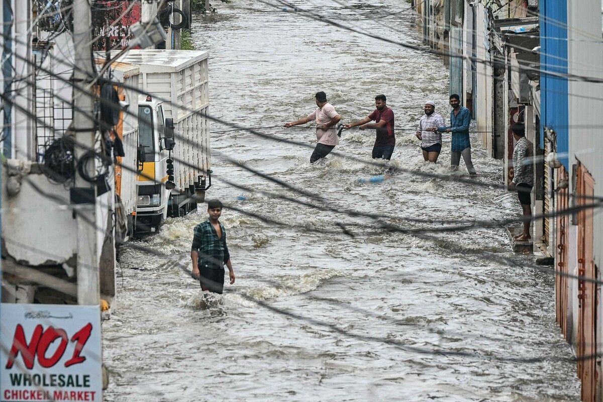 Anwohner waten durch eine überflutete Straße, nachdem der Musi-Fluss nach starken Monsunregenfällen in Hyderabad über die Ufer getreten ist.