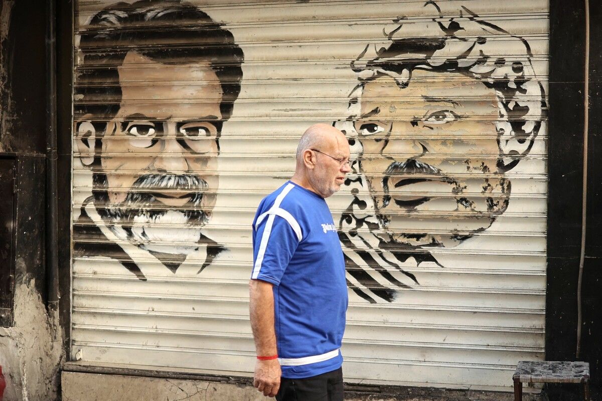 Ein Palästinenser geht in Ramallah an Porträts von Saddam Hussein und Jassir Arafat auf der Tür eines geschlossenen Ladens vorbei.