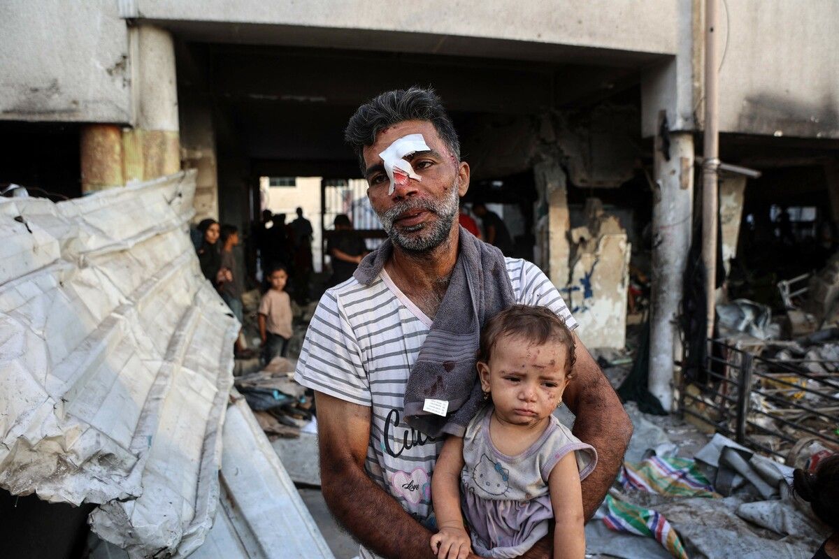 Ein verletzter Palästinenser sitzt mit seiner Tochter vor den Trümmern der Al-Farabi-Schule in Gaza, die nach erneuten israelischen Angriffen als Unterkunft dient. afp