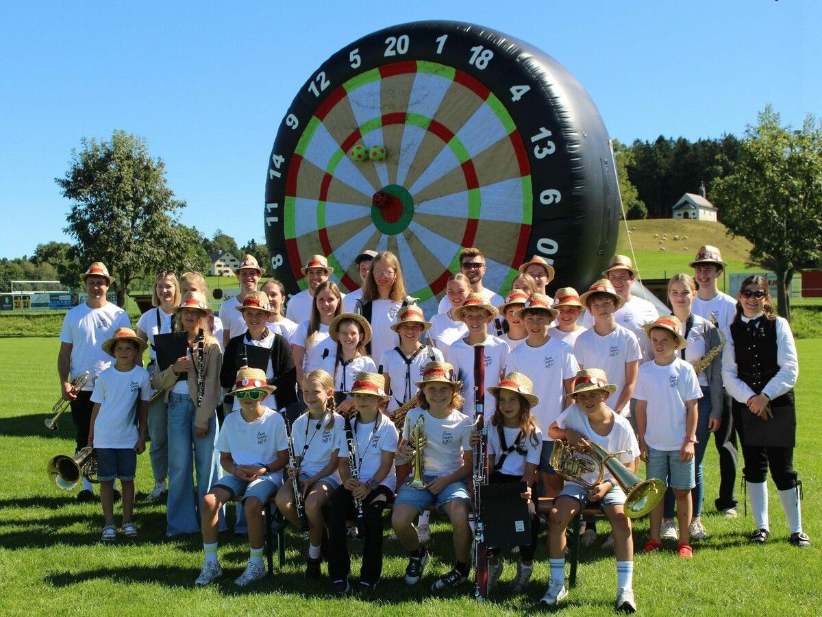 Gruppenbild der Jugendmusik „Zemma sind mir MEH“ vor der riesigen Fußball-Dart-Scheibe.⇒ Peter Strauss (3)