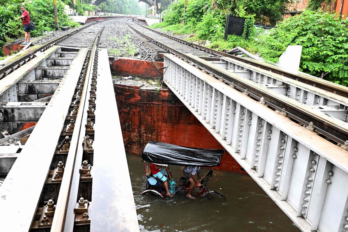 Pendler fahren nach heftigem Monsunregen per Rikscha über eine überflutete Straße in Kolkata.