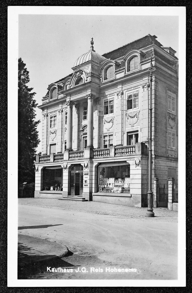 Das Geschäftshaus J.G. Reis wurde 1903 nach den Plänen des Architekten Hanns Kronberger im Stil des Historismus umgestaltet. 1962/63 wurde es zum heutigen Sparkassengebäude umgebaut.⇒⇒Ansichtskartensammlung Richard Huter, Vorarlberger Landesbibliothek; Oskar Span, Stadtarchiv Bregenz