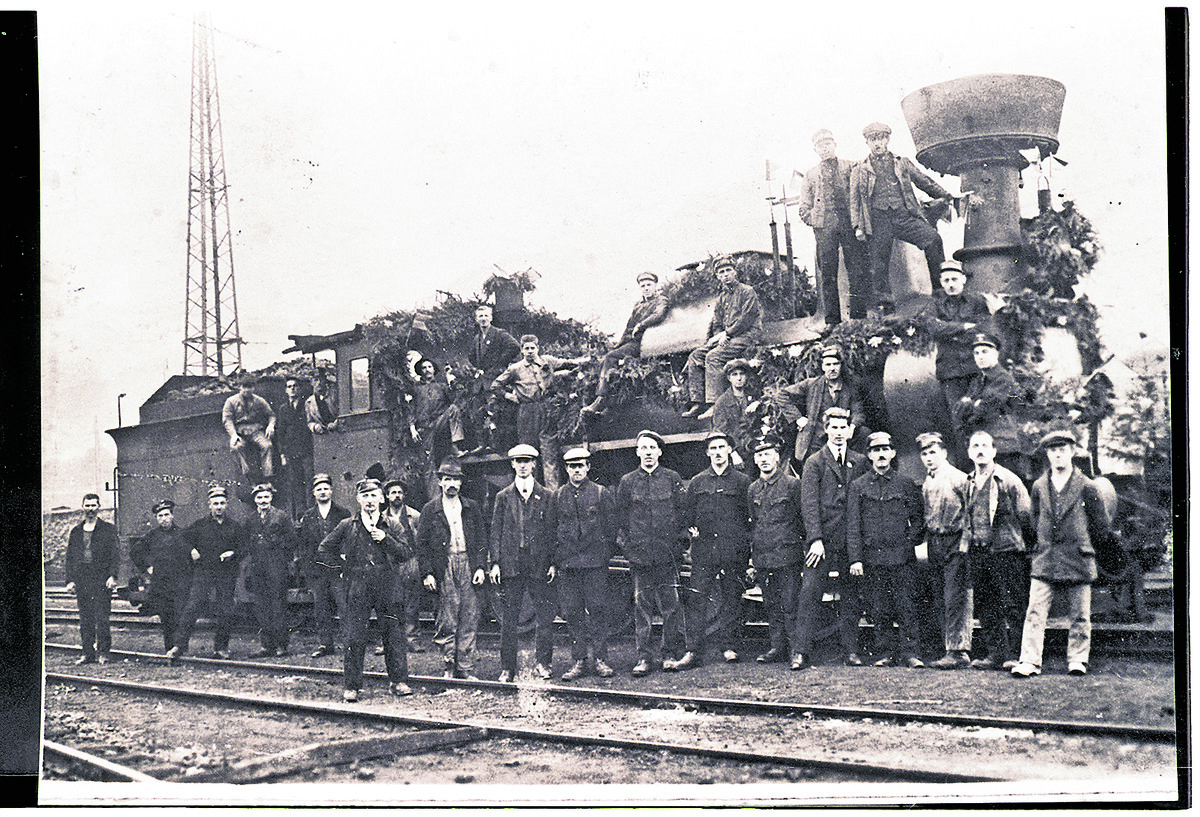Feierlich geschmückt und dicht belagert: Eine Lokomotive der Arlbergbahn, vermutlich um 1884, flankiert von Arbeitern und Technikern – ein seltener Einblick in den Stolz der Bahnarbeiter auf das Gelingen des Großprojekts.⇒Fotoarchiv der Johann-August-Malin-Gesellschaft, Vorarlberger Landesbibliothek