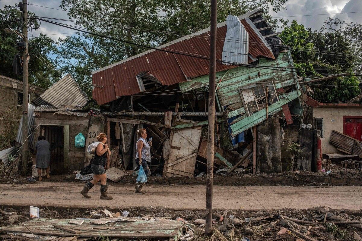 Zwei Frauen gehen an einem durch heftige Überschwemmungen beschädigten Haus im Stadtteil Las Granjas in Poza Rica im mexikanischen Bundesstaat Veracruz vorbei.