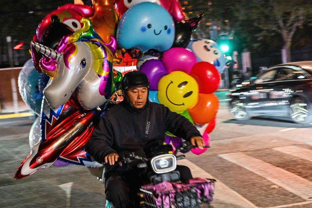 Ein Ballonverkäufer fährt mit einem Motorroller durch die Straßen des Bezirks Xuhui in Shanghai.