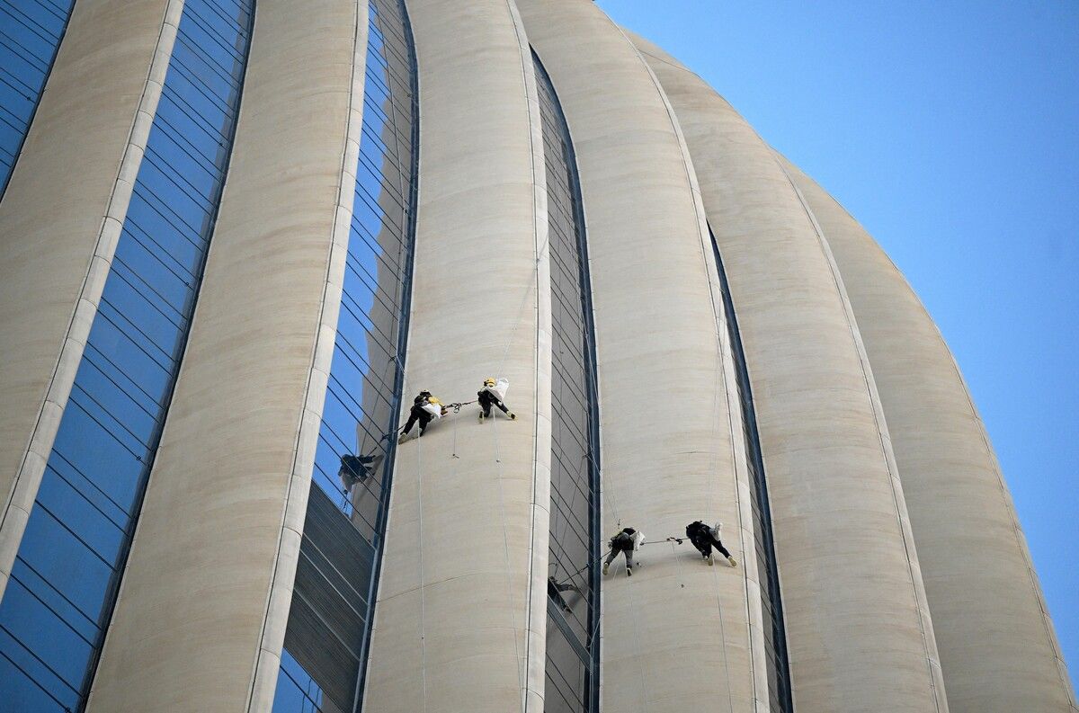 Industriekletterer bereiten sich darauf vor, die Glasfassade der Zentrale der Nationalbank in Kuwait-Stadt zu reinigen.