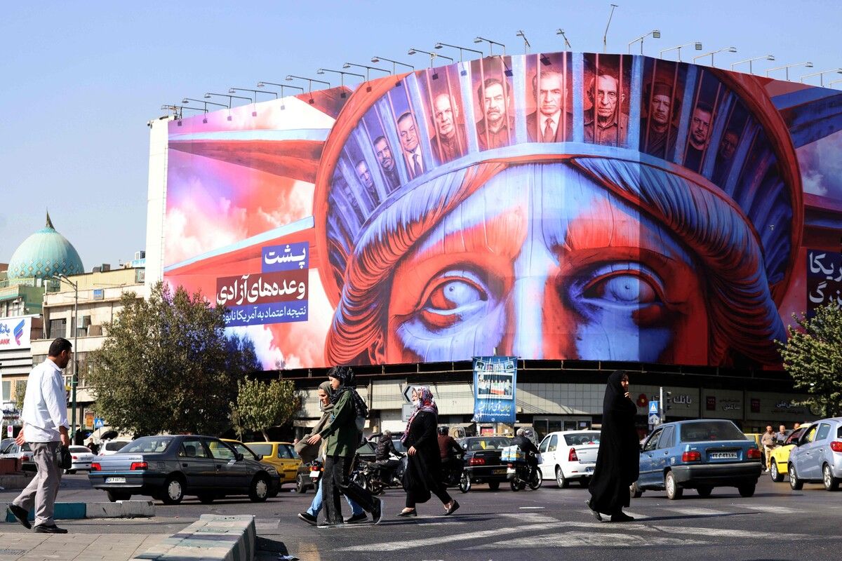Menschen gehen an einem Banner mit der Freiheitsstatue und dem persischen Schriftzug „Das Versprechen amerikanischer Freiheit“ am Enghelab-Platz in Teheran vorbei. AFP (5)  