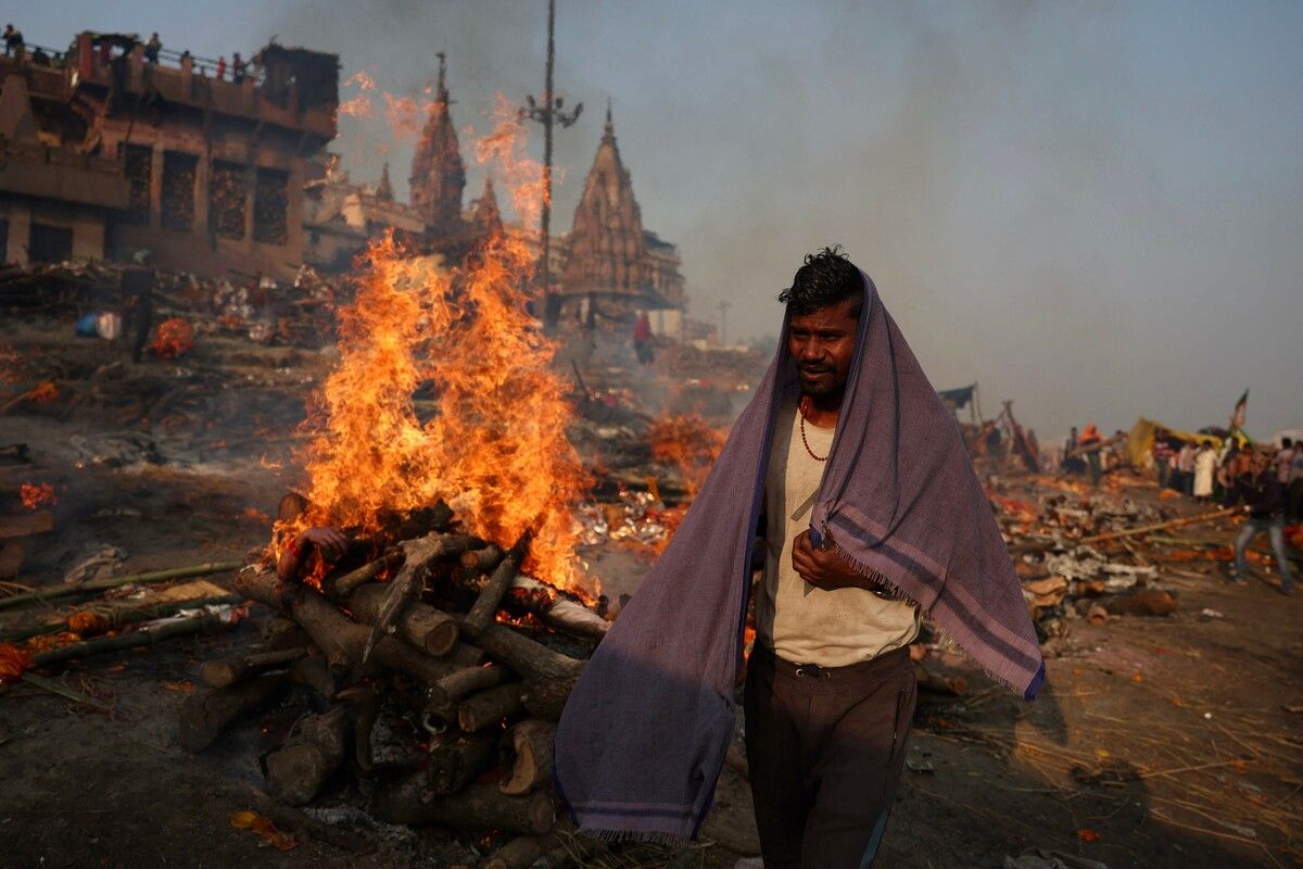 Ein Kremator der Dom-Gemeinschaft geht an den brennenden Scheiterhaufen am Manikarnika Ghat am Ufer des Ganges in Varanasi vorbei. AFP (5)