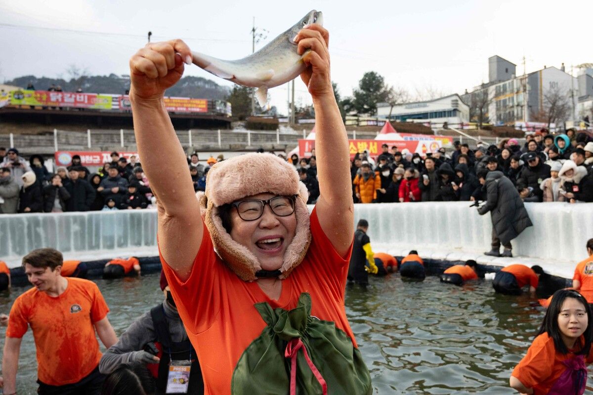 Eine Frau jubelt, als sie während des jährlichen Eisfischfestivals in Hwacheon in Südkorea eine Forelle mit der Hand fängt.