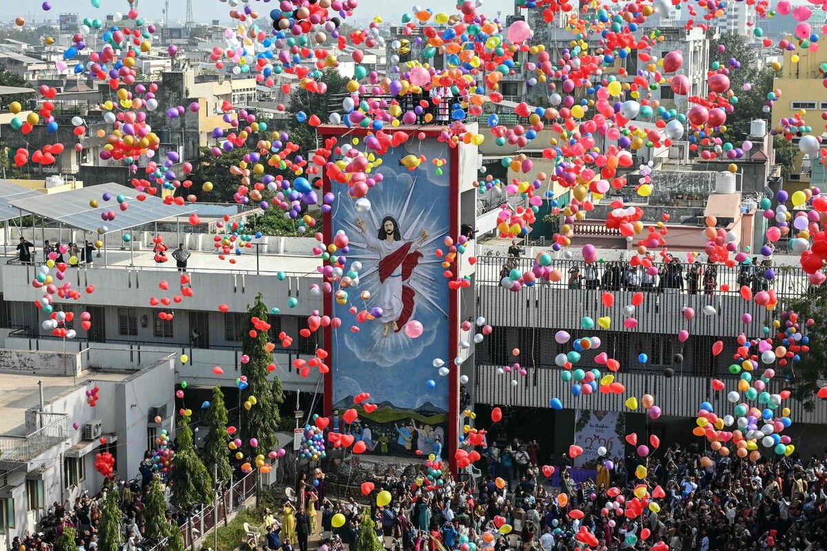 Menschen lassen bei Neujahrsfeiern in einer Kirche in Ahmedabad bunte Ballons steigen und drücken gemeinsam Hoffnung, Freude und Gemeinschaft in festlicher Glaubensstimmung aus.