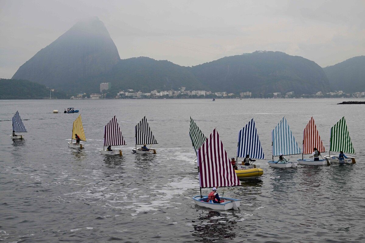 Segelboote mit markant gestreiften Kunstsegeln gleiten über die Bucht von Rio, wo sich Kunst und Segelsport zu einer farbstarken Performance verbinden.