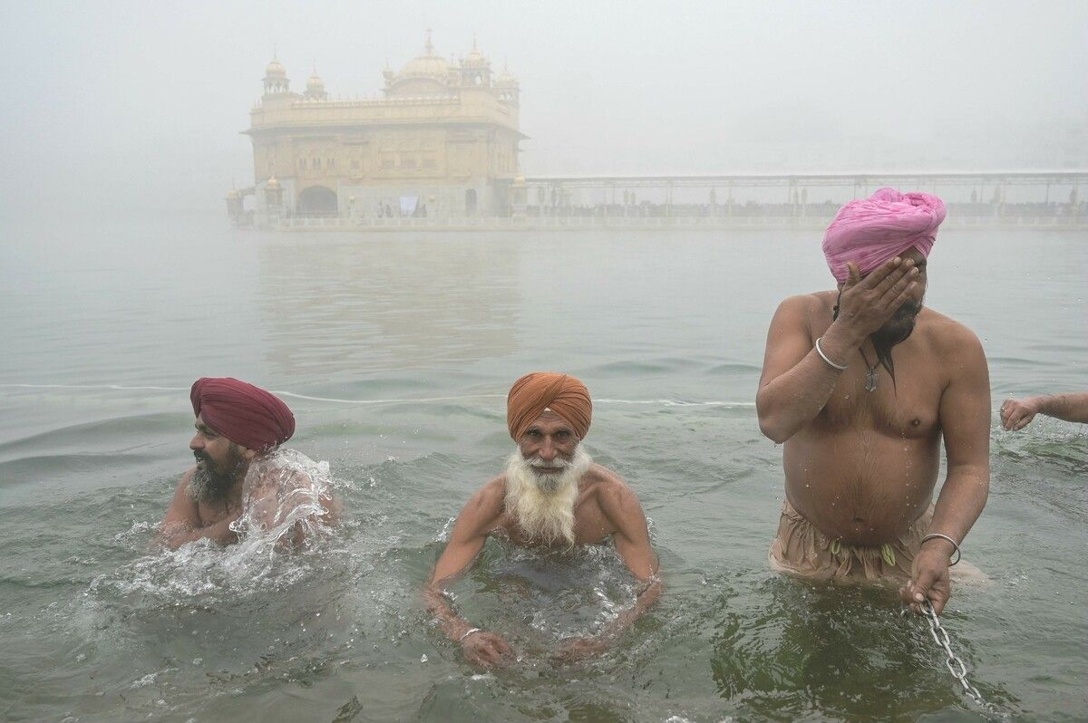 Sikh-Gläubige baden zum Maghi-Fest im heiligen See am Goldenen Tempel in Amritsar – dichter Nebel liegt in der Luft.
