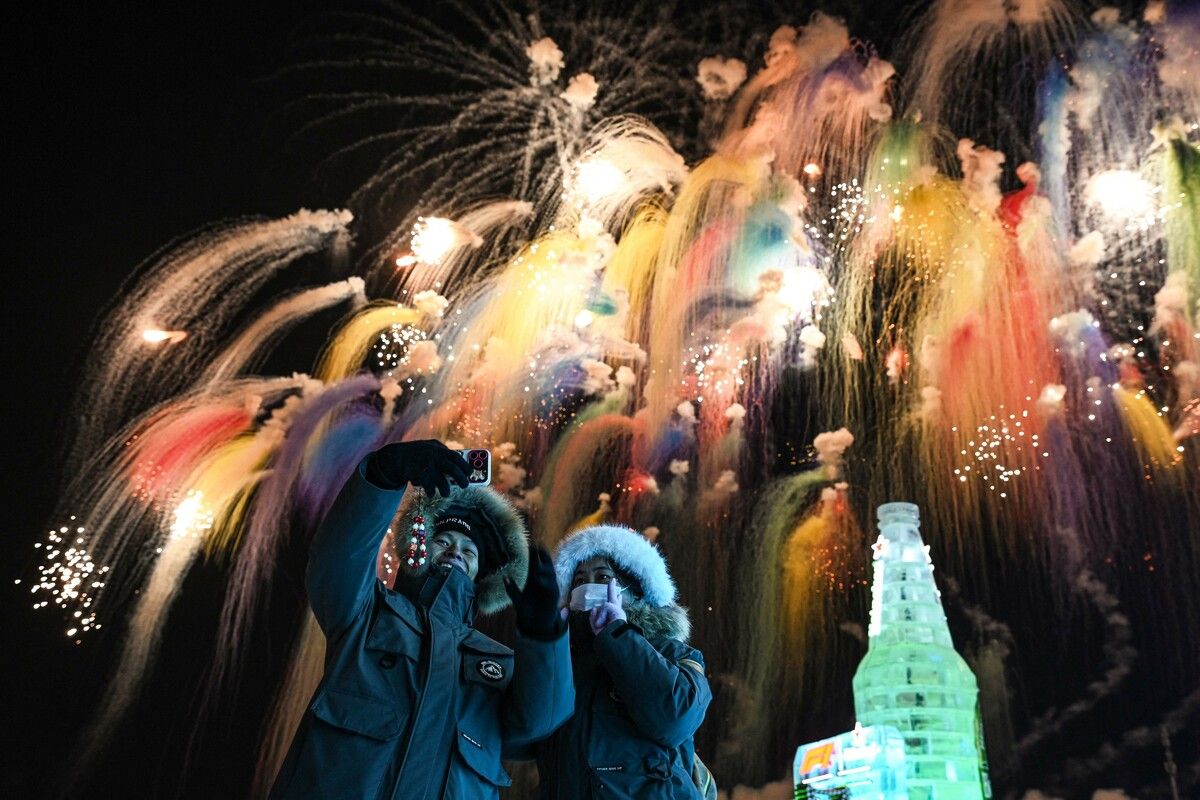Zwei Jugendliche machen ein Selfie vor deinem Feuerwerk während der Eröffnungszeremonie des 42. Internationalen Eis- und Schneefestivals von Harbin in China.