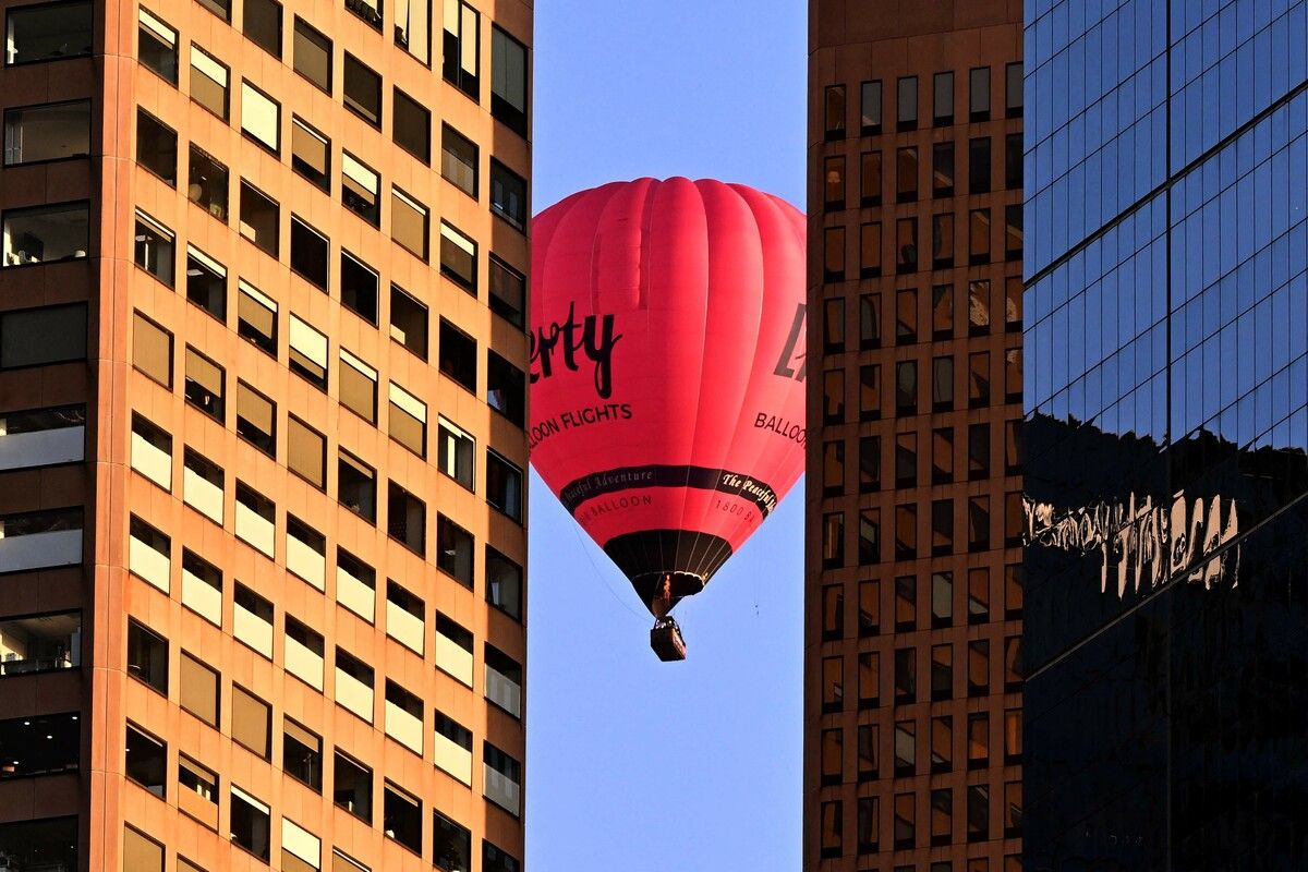 Ein Heißluftballon mit Touristen schwebt am frühen Morgen an der Skyline des Geschäftsviertels von Melbourne vorbei.
