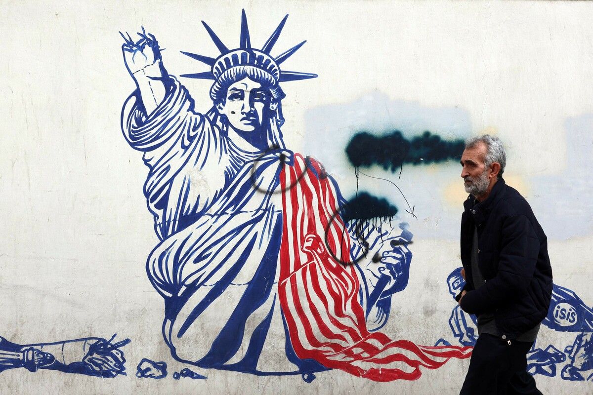 Ein Mann passiert ein Mural der Freiheitsstatue mit gebrochenem Arm an der ehemaligen US-Botschaft in Teheran, während Iran und USA verhandeln und Washington militärische Optionen offenlässt.