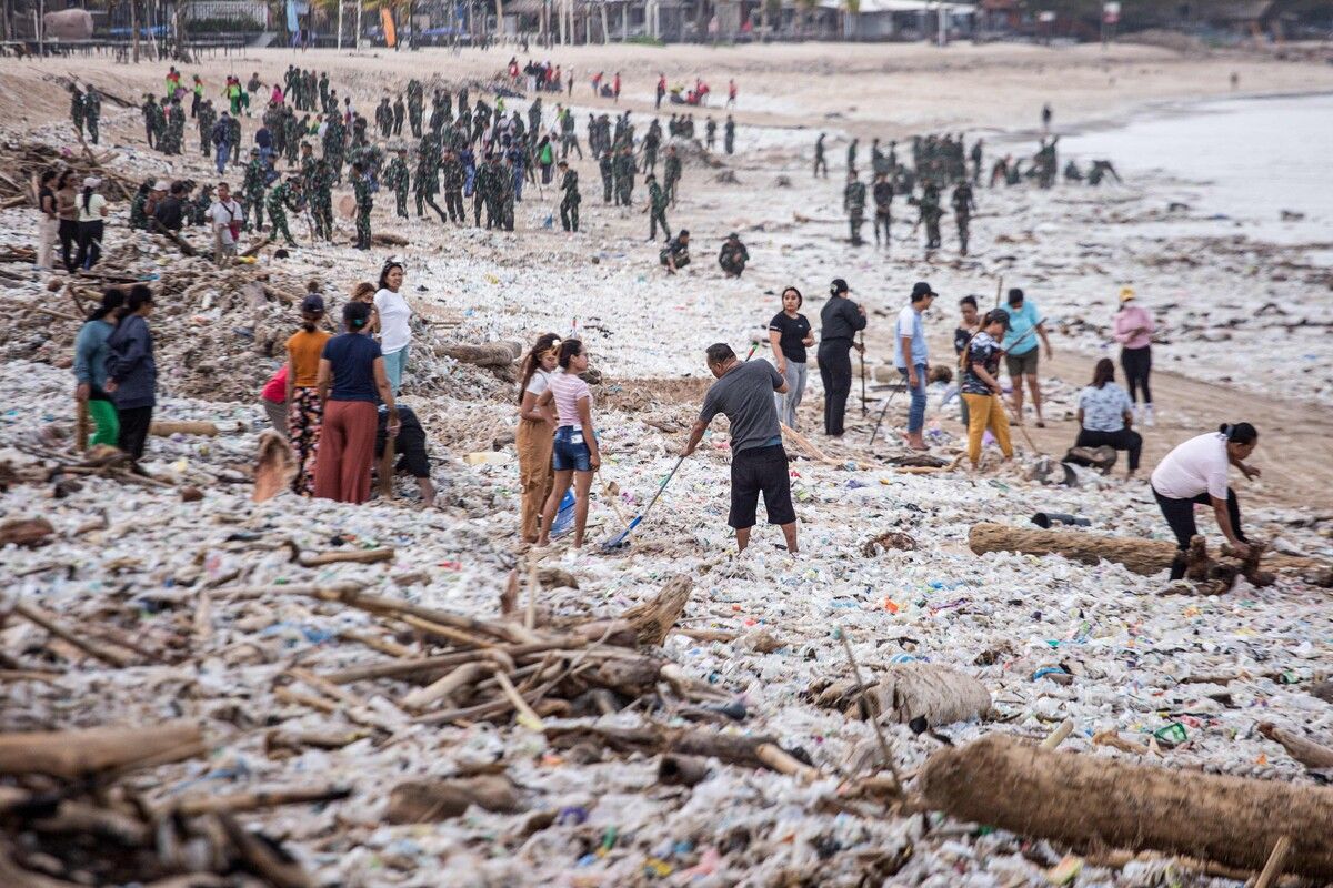 Arbeiter und Anwohner räumen während der Monsunzeit angeschwemmten Müll und Plastik vom Strand von Jimbaran auf Bali.