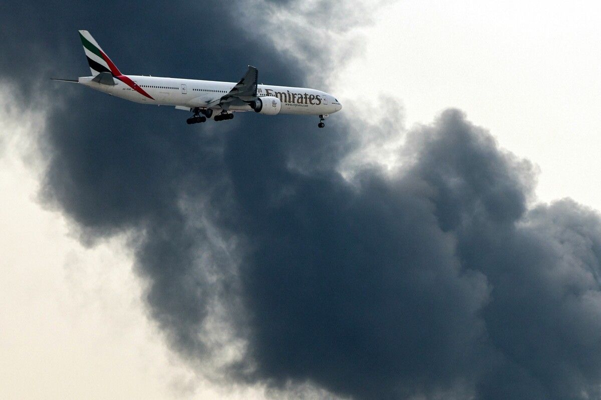 Ein Airbus A350 von Emirates setzt zur Landung an, während eine Rauchwolke von einem Brand am Flughafen Dubai aufsteigt.