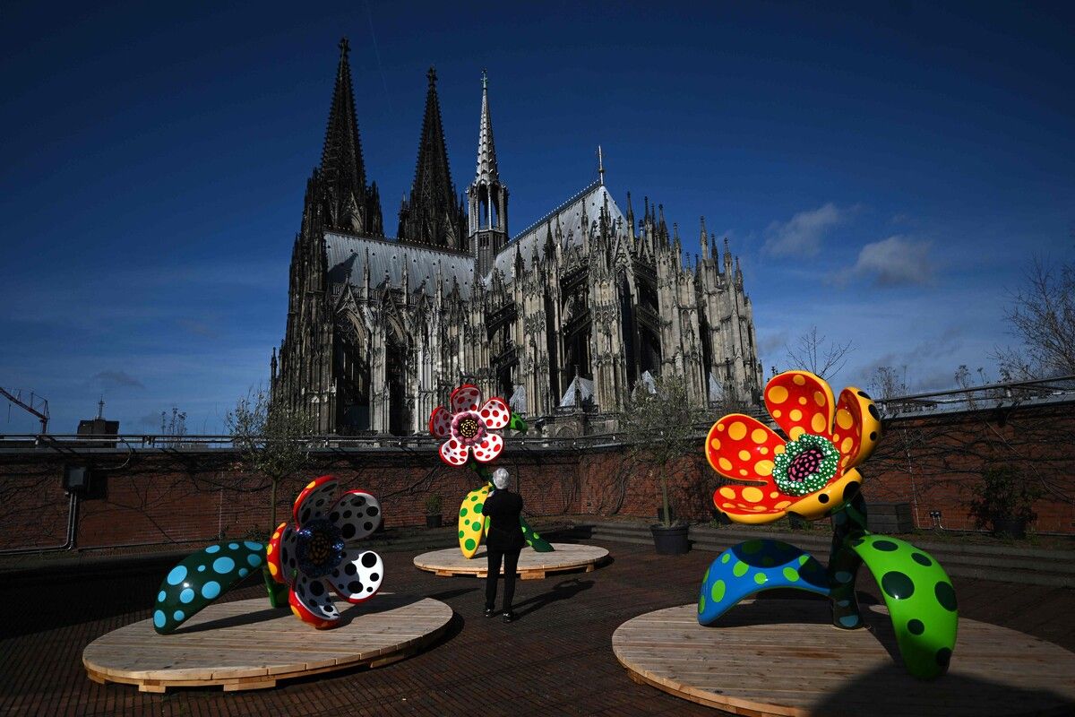 Ein Besucher fotografiert die Installation „Flowers that speak all about my heart given to the sky“ vor dem Kölner Dom. AFP (5)