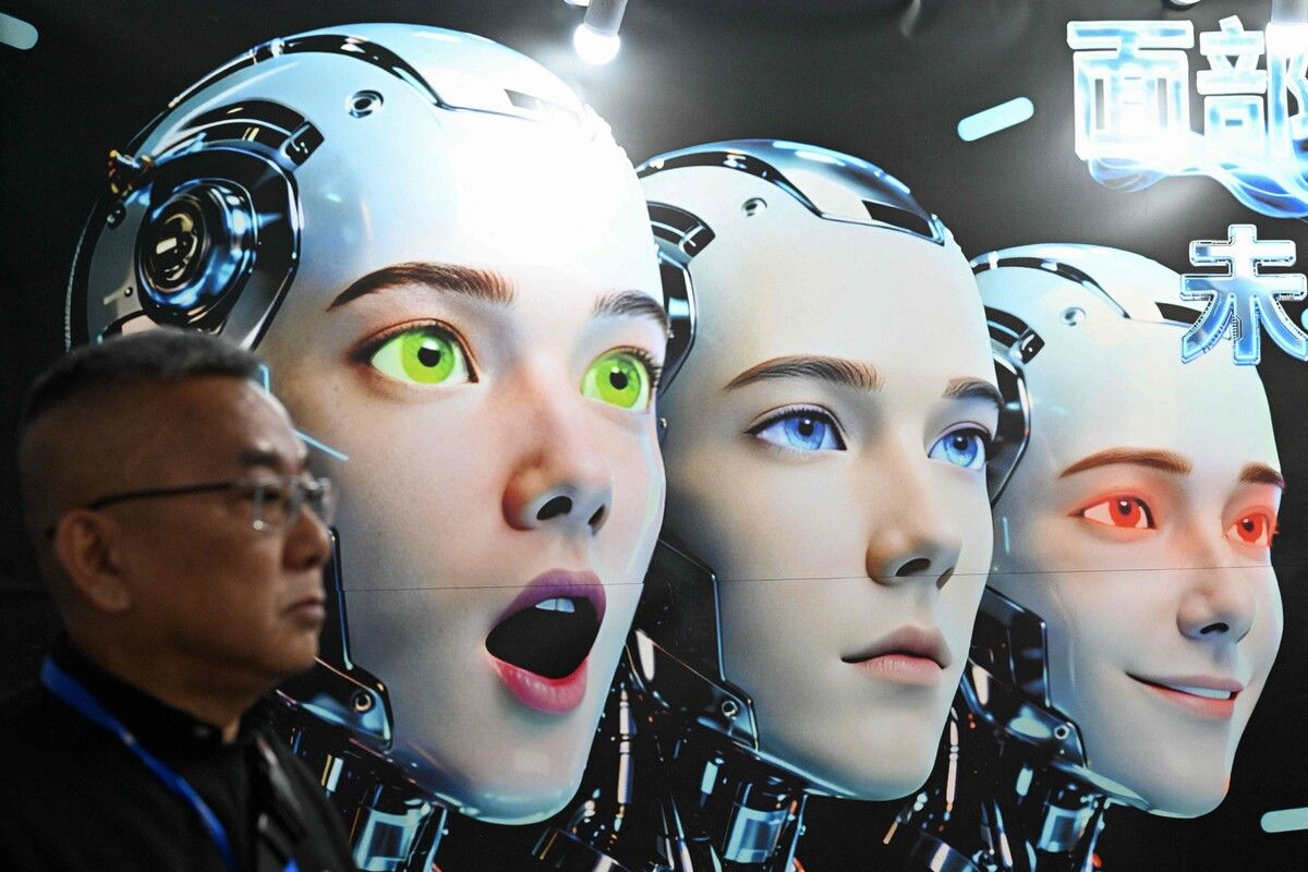 Ein Mann steht auf der KI- und Robotikmesse in Peking neben einem Poster mit Robotern, die menschliche Mimik zeigen. AFP (5)