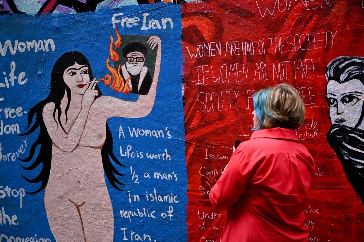 Eine Touristin fotografiert ein Street-Art-Werk zu den aktuellen Anti-Regierungsprotesten im Iran in Melbournes Hosier Lane.