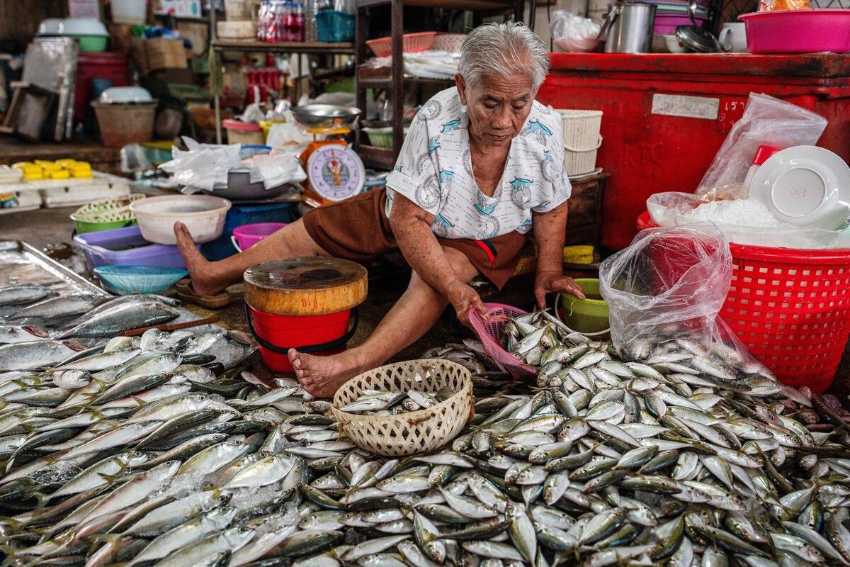 Eine Fischhändlerin in Thailand bereitet ihre Ware auf einem Frischmarkt für den Verkauf vor.