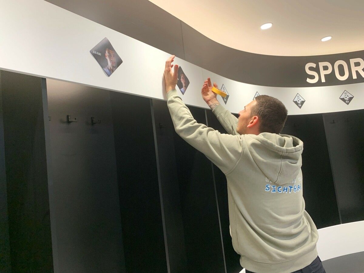 Letzte Arbeiten in der neuen Mannschaftskabine, wo die Spielerfotos an ihren Plätzen angebracht wurden.