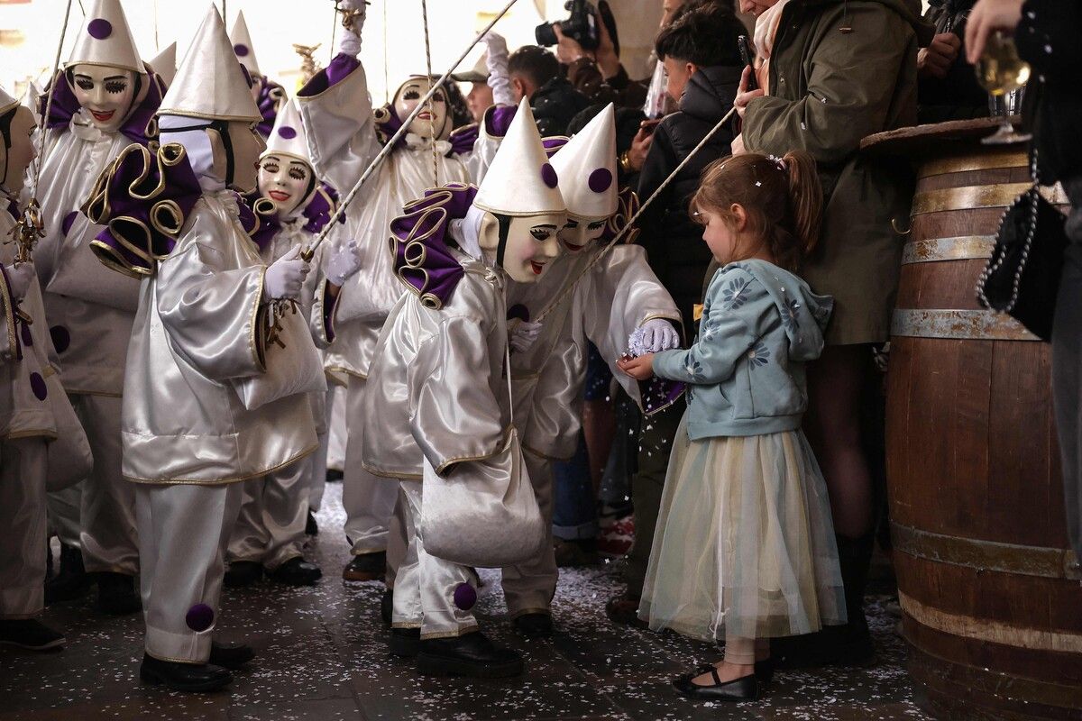 Maskierte Teilnehmer des traditionellen Stadtkarnevals in Limoux in Südfrankreich schenken einem Mädchen Konfetti.