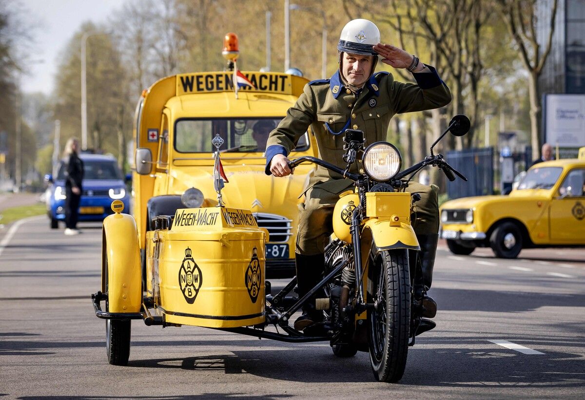 Ein Pannenhelfer fährt zum 80-jährigen Jubiläum der Pannenhilfe in den Niederlanden in historischer Kleidung auf einem Oldtimer-Motorrad.
