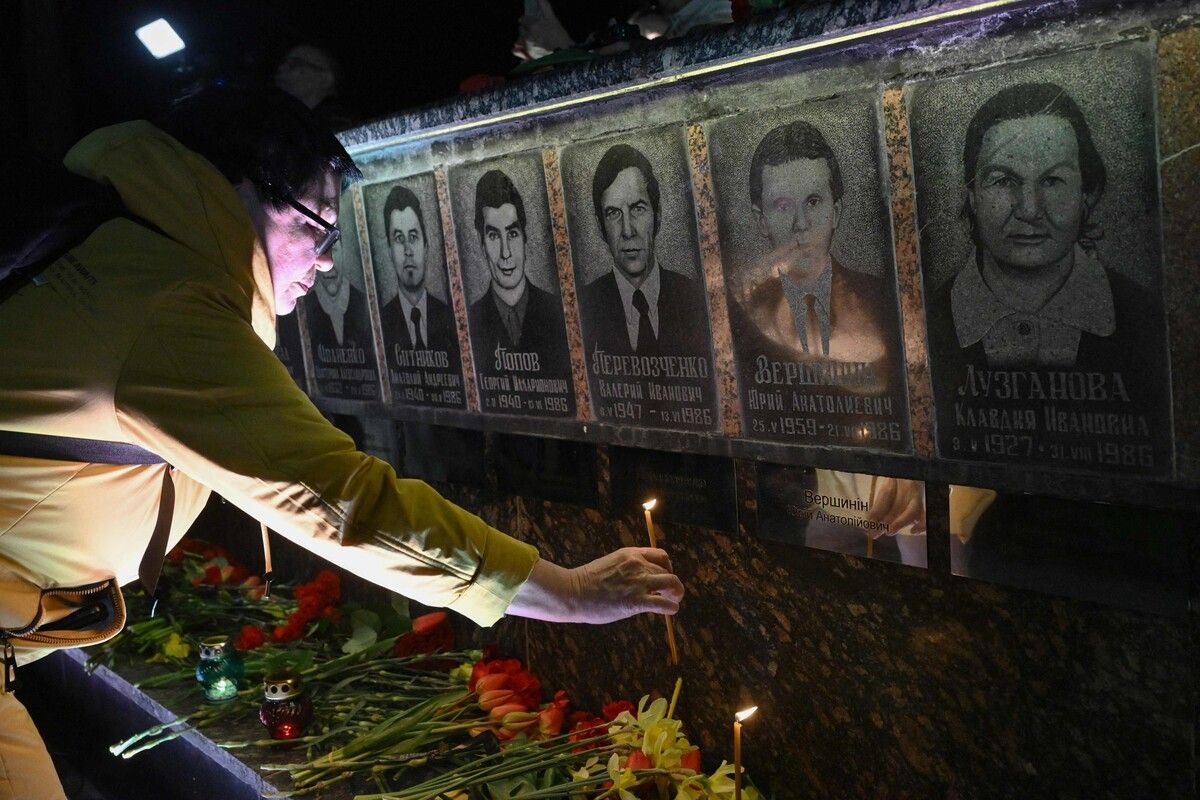 Eine Frau stellt in Slawutytsch bei der Gedenkfeier zum 40. Jahrestag der Tschernobyl-Katastrophe eine Kerze vor ein Denkmal für die Opfer auf. 