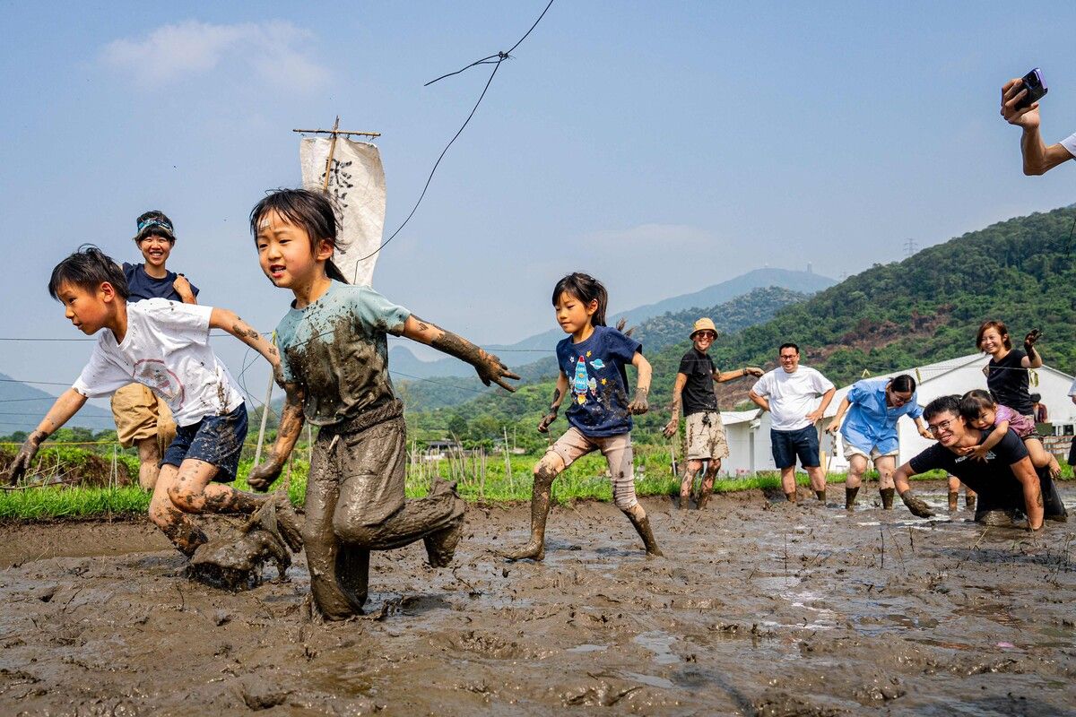 Kinder nehmen an ausgelassenen Schlammspielen und -rennen bei einem organisierten Event in Hongkong teil.