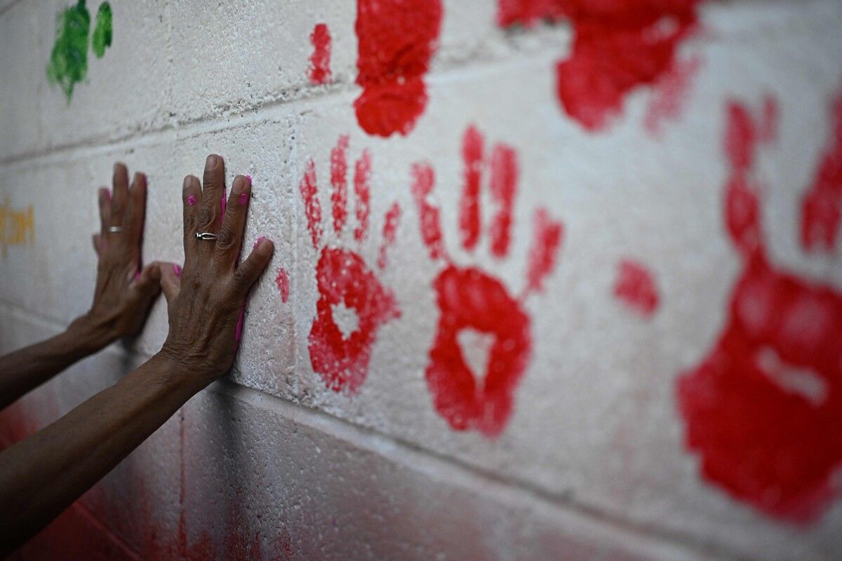 Mutter eines Vermissten setzt Handabdrücke auf Gedenk-Mauer in El Salvador. Tausende verschwanden im Bandenkrieg.