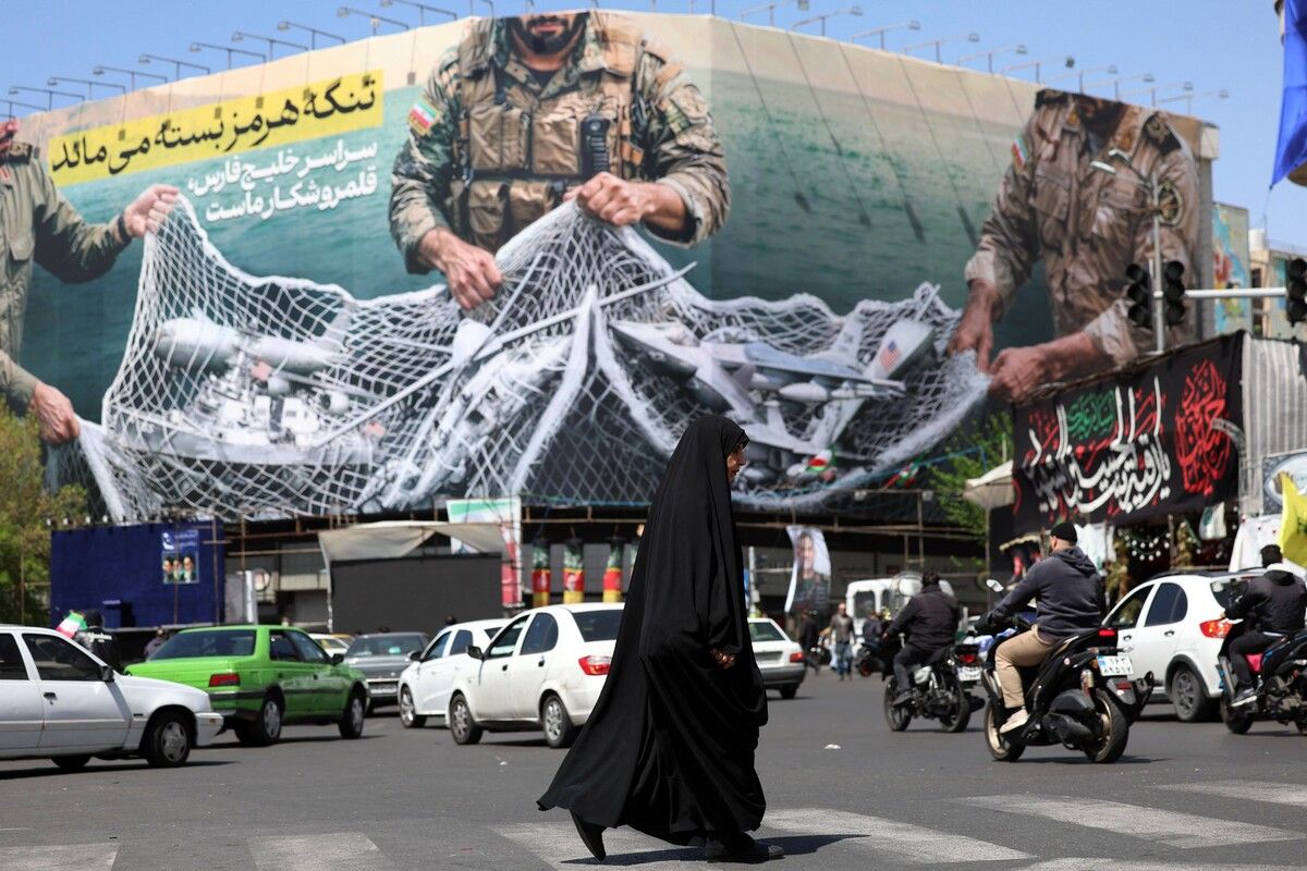Passanten gehen am Enghelab-Platz in Teheran an einer Propaganda-Werbetafel mit der Aufschrift „Die Straße von Hormuz bleibt geschlossen“ vorbei.