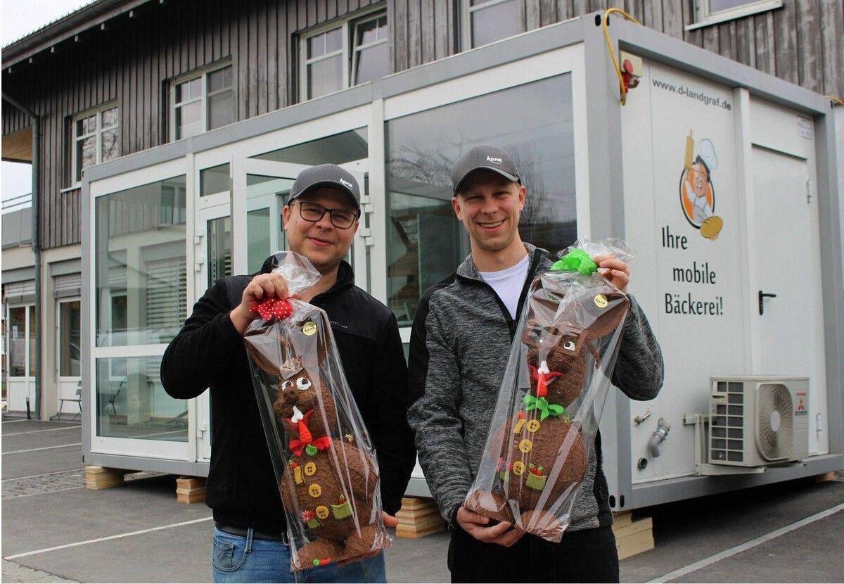 Vor dem Verkaufscontainer, in dem die Kundinnen und Kunden bedient werden, präsentieren Dominik und Michael Künz stolz die größten Meisterwerke aus der nagelneuen Konditorei, dem „Hasen-Keller“: jeder Hase 55 cm hoch und 1,75 kg schwer. ⇒stp (3)