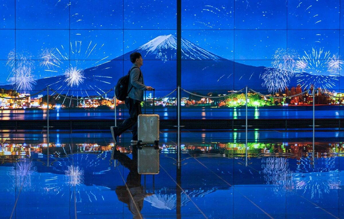 Ein Reisender läuft im Ankunftsbereich des Haneda-Flughafens in Tokio an einem Bild des Mount Fuji vorbei. AFP (5)