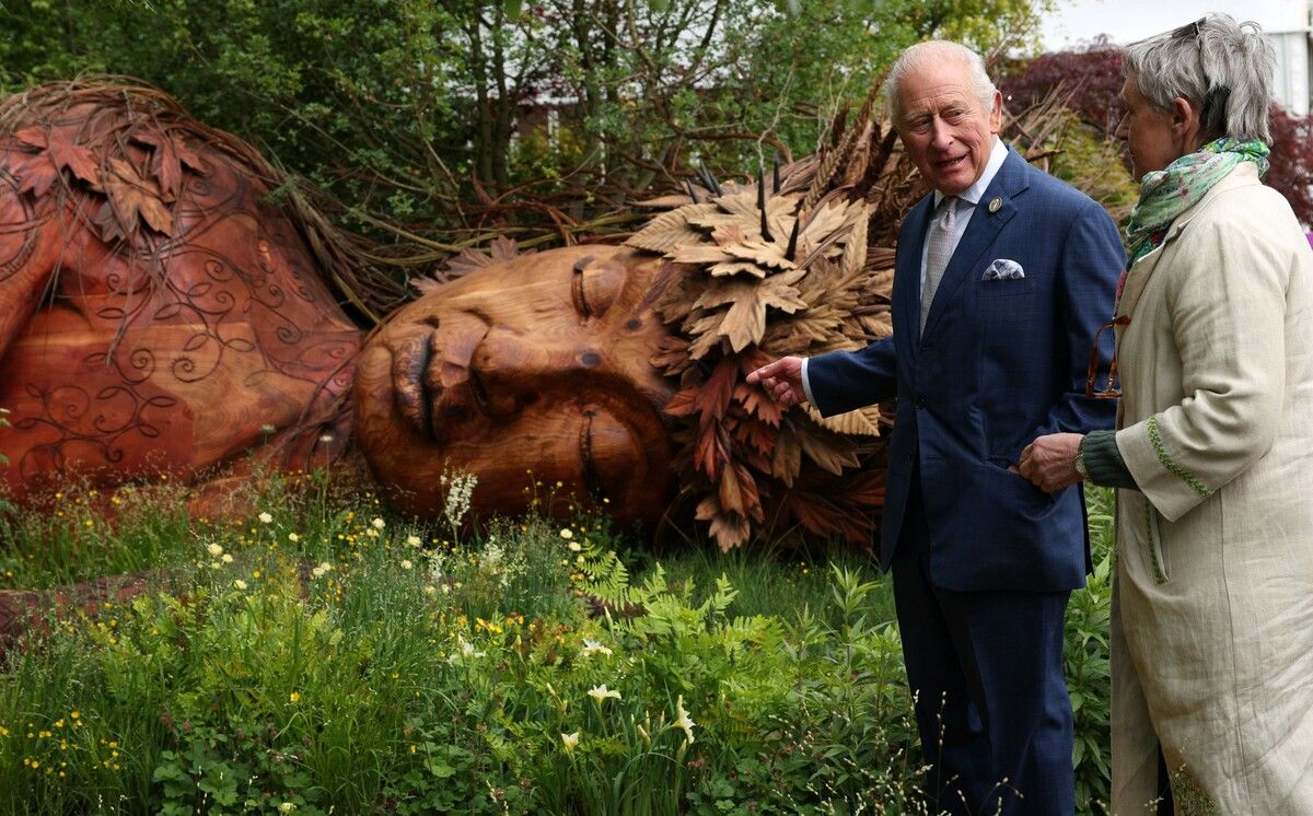 König Charles III spricht vor einer riesigen Holzskulptur mit der Gartengestalterin im „On the Edge“-Garten der RHS Chelsea Flower Show in London. AFP (5)