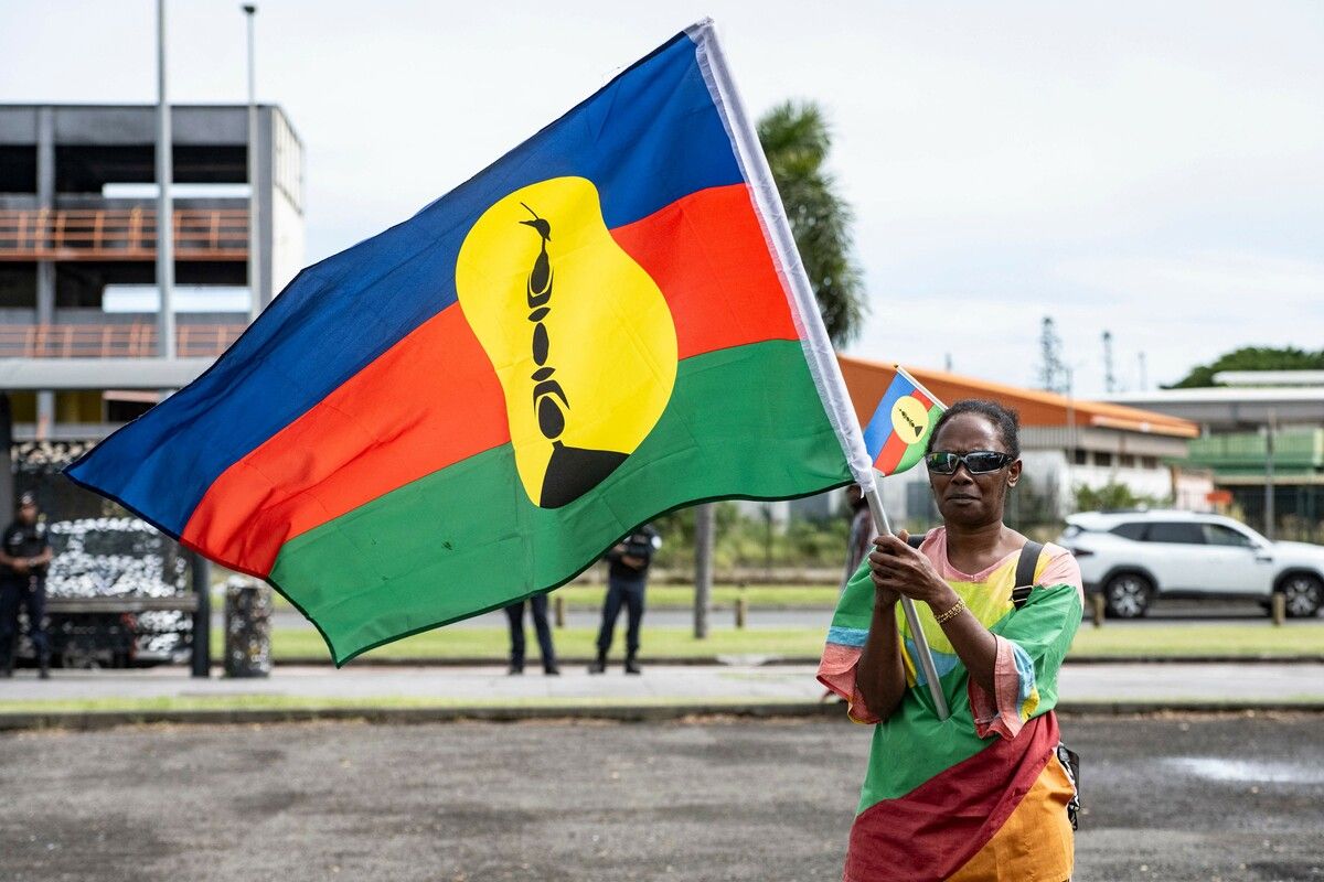 Pro-Unabhängigkeitsaktivist schwenkt Flagge bei Demo zum 2. Jahrestag der Unruhen 2024 in Nouméa, Neukaledonien. Spannungen bestehen weiter.