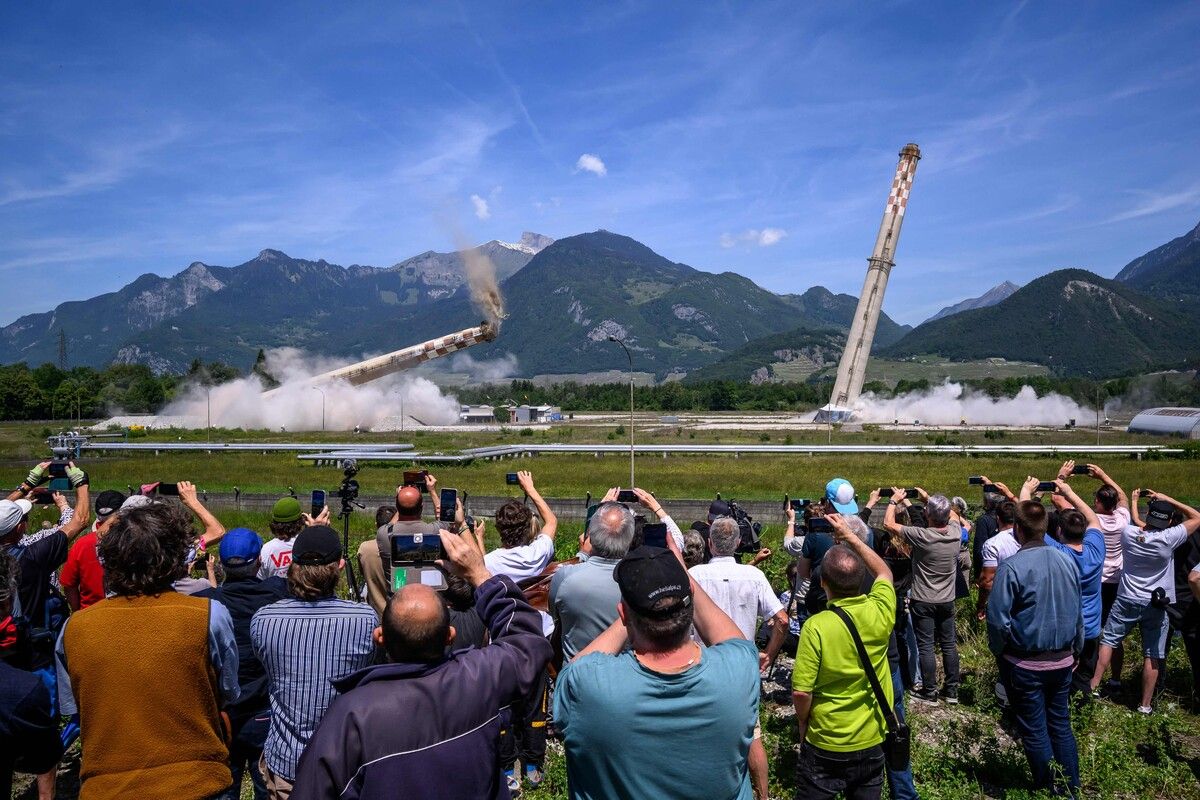 Zuschauer beobachten die kontrollierte Sprengung der beiden 100 Meter hohen Schornsteine einer ehemaligen Raffinerie in Collombey-Muraz in der Schweiz.