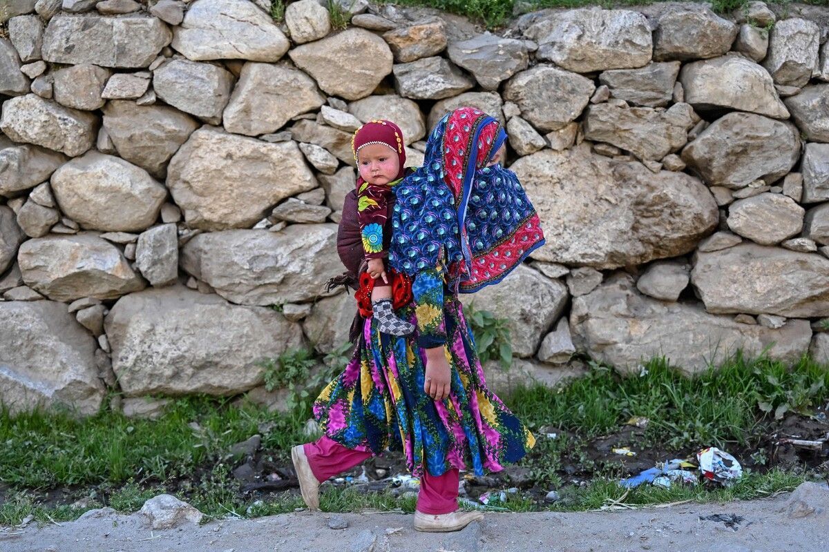 Ein afghanisches Mädchen trägt in der Provinz Nuristan ein Kind auf dem Rücken.