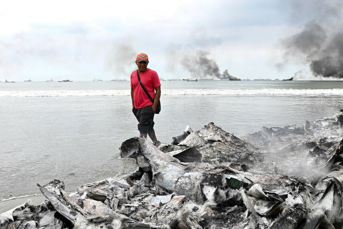 Ein Mann betrachtet die Überreste eines ausgebrannten Fischerbootes in der Nähe des Hafens von Manta in Ecuador, wo am Wochenende ein Großbrand wütete. AFP (5)