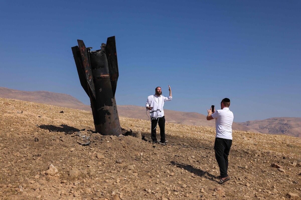 Ein Mann posiert neben einer halb im Boden steckenden Rakete nahe Jericho nach Angriffen Irans und der Huthi-Rebellen für ein Foto. AFP (5)