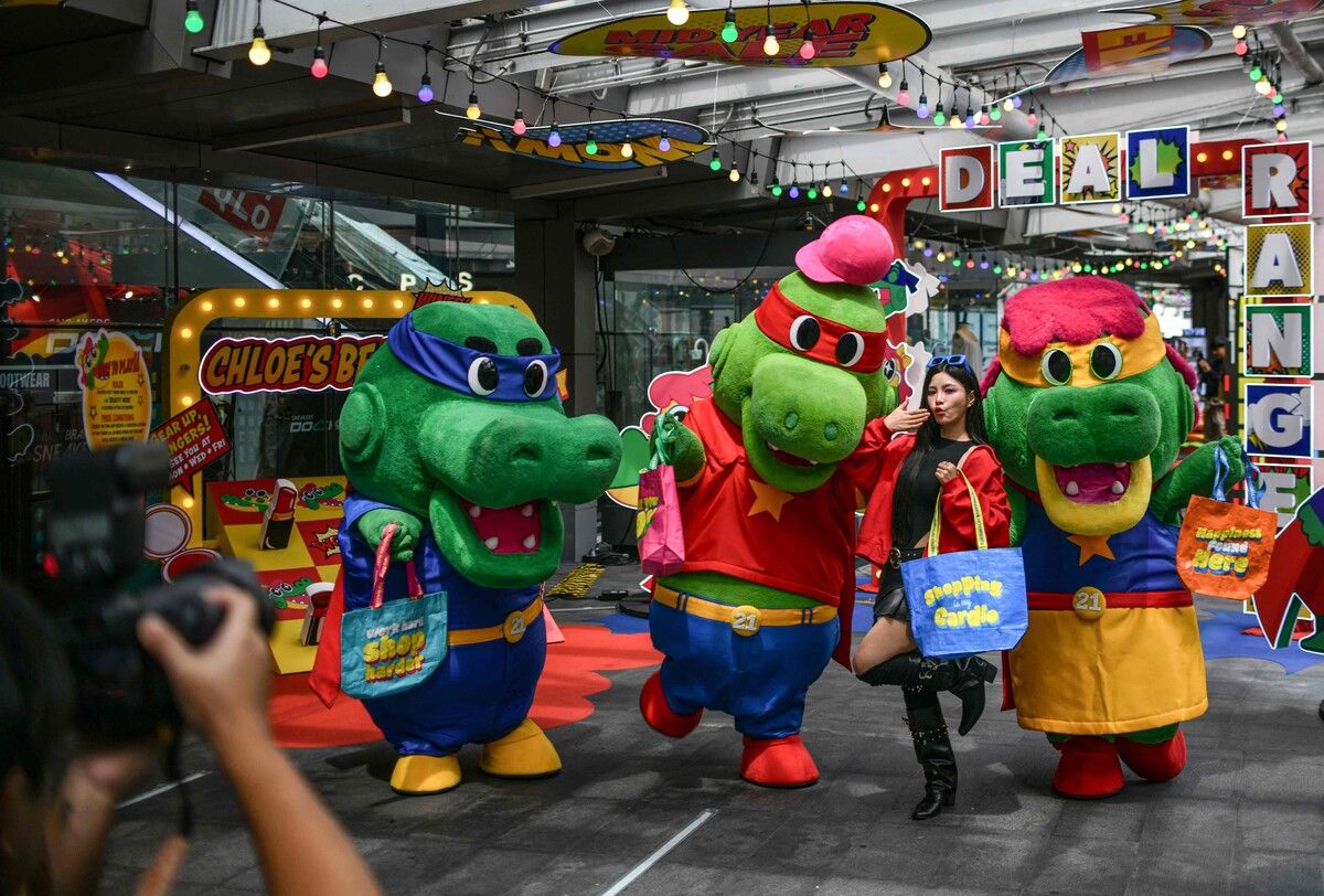 Ein Model posiert mit Krokodil-Maskottchen vor einem Einkaufszentrum in Bangkok. Die auffällige Aktion soll die Aufmerksamkeit von Kunden auf Verkaufsangebote lenken.