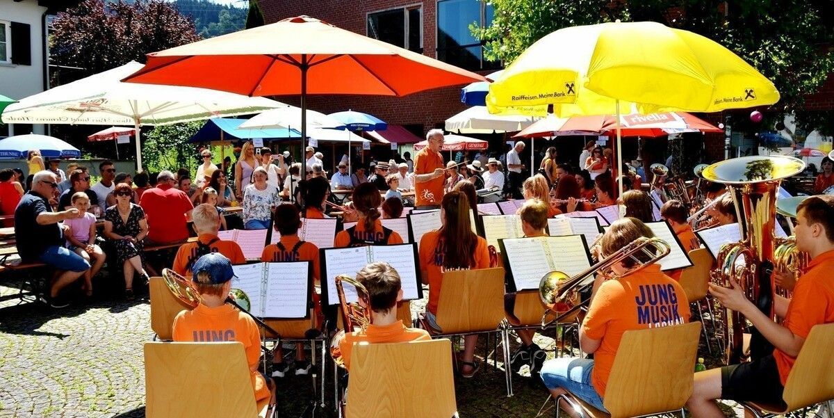 Einladung zum Sommerfest der Pfarre Lochau auf dem Platz vor dem Pfarrheim Franz Xaver – ein blasmusikalischer Frühschoppen in geselliger Atmosphäre.⇒bms